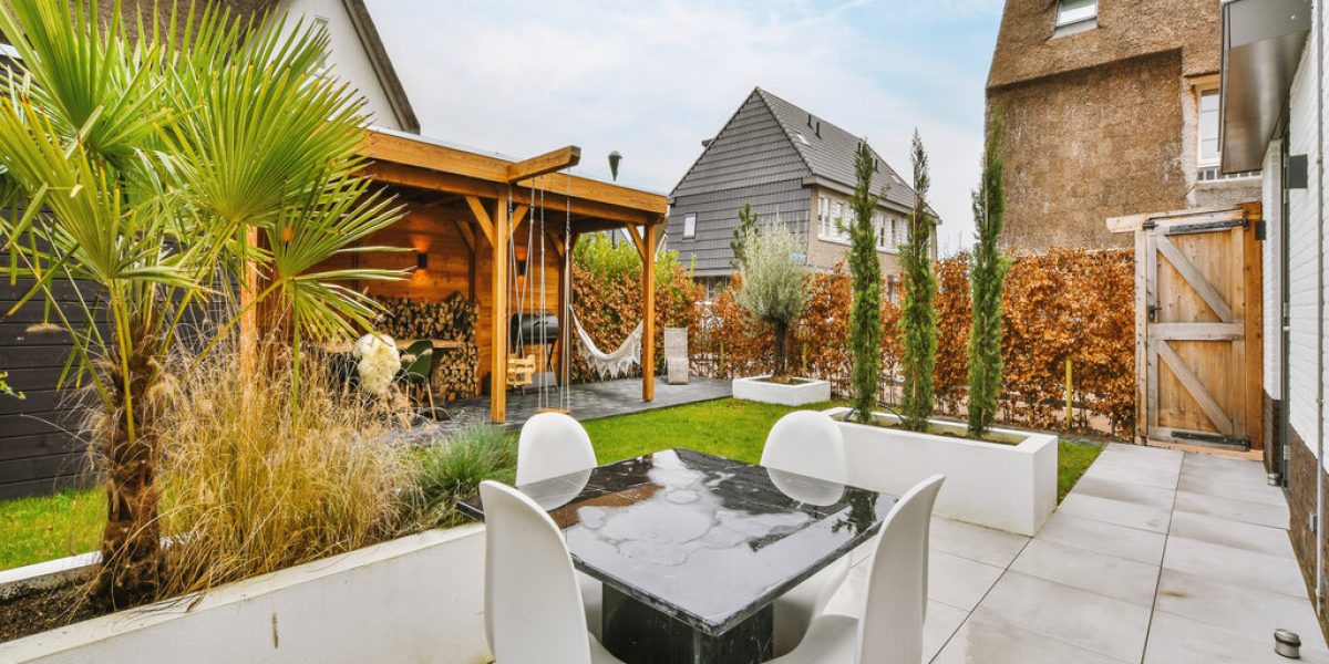 Neat paved patio with sitting area and small garden near wooden fence